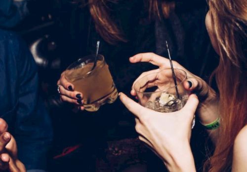 People laughing and enjoying drinks at a social gathering or party setting.
