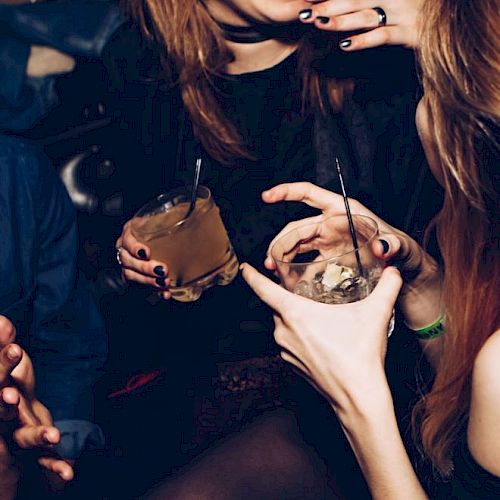 People laughing and enjoying drinks at a social gathering or party setting.
