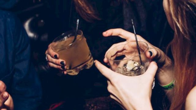People laughing and enjoying drinks at a social gathering or party setting.