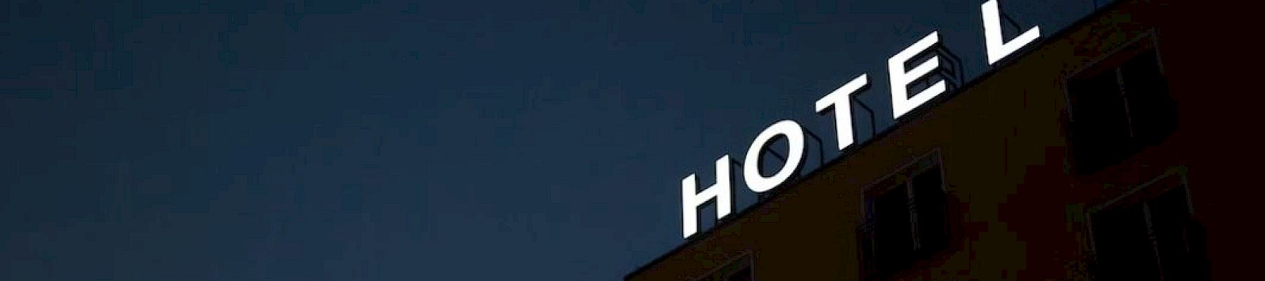 A building with a glowing "HOTEL" sign against a dark sky.