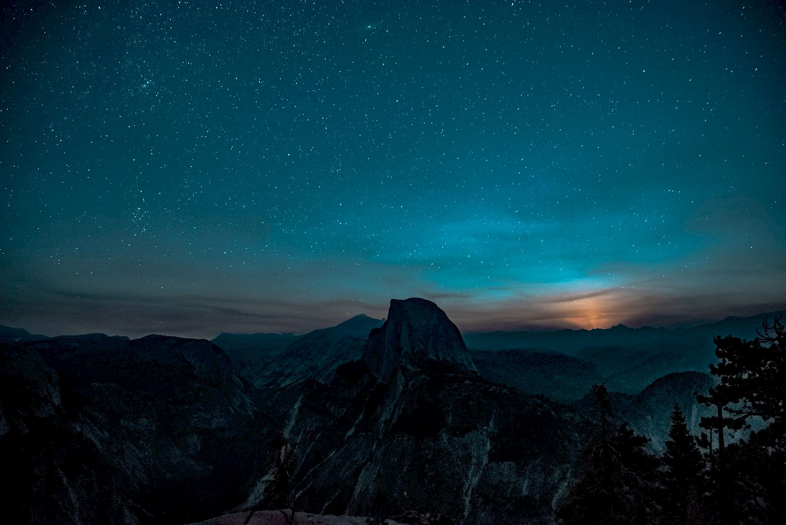 A starry night sky with a silhouette of mountains and a glowing horizon, creating a tranquil and scenic view.