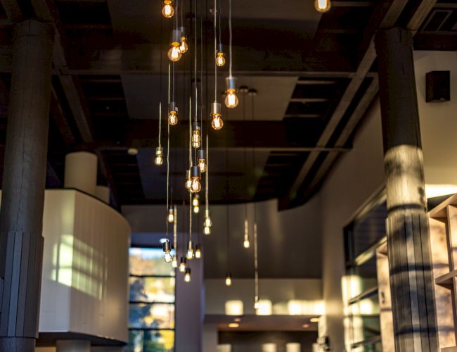 A chic interior with hanging Edison bulbs, exposed beams, warm lighting, and modern decor creating an industrial cozy vibe.