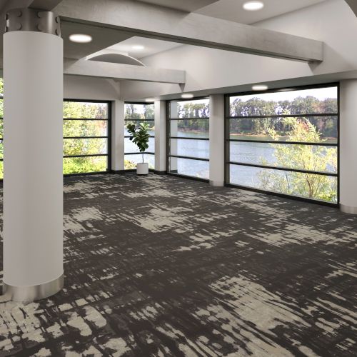 An empty room with large windows, patterned carpet, white pillars, plants, and a scenic view outside.