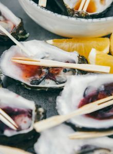 The image shows a plate of oysters on ice, served with lemon wedges and wooden picks.