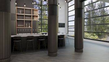 The image shows a modern, spacious room with large windows, a bar area, stools, and dark wooden accents.
