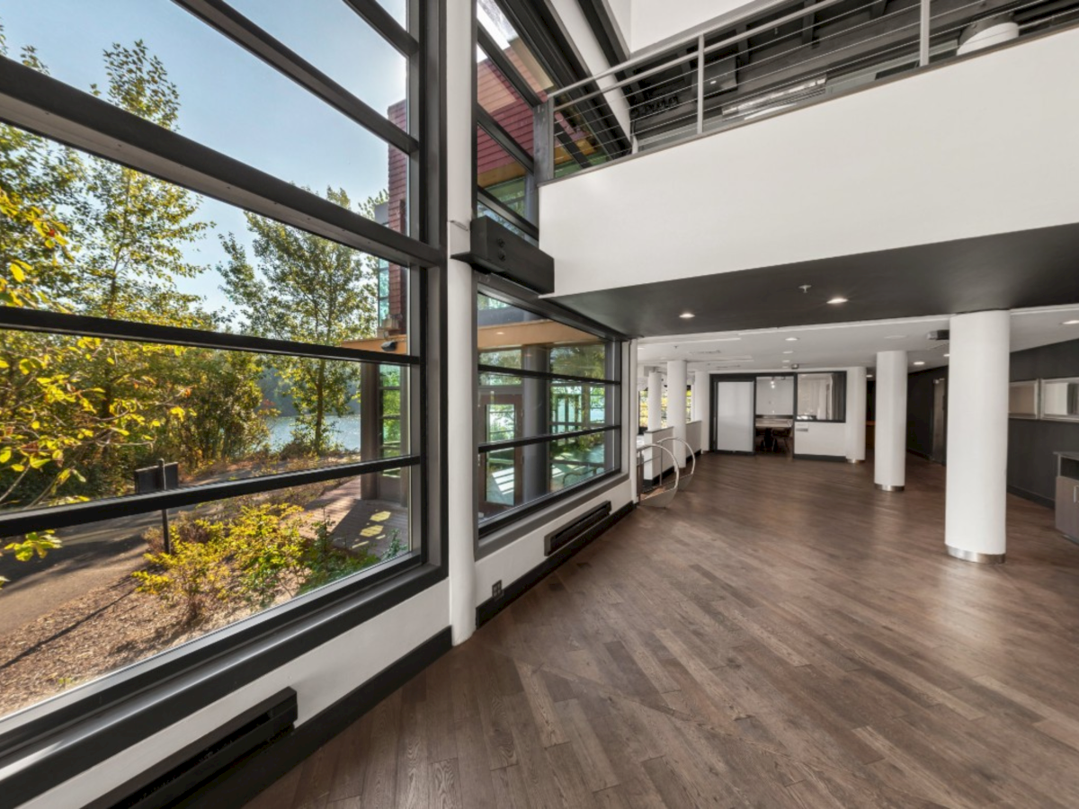 Bright modern interior hallway with tall pillars, large windows, and dark trim overlooking greenery.