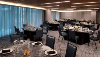 The image shows a formal dining setup in a spacious room with elegantly decorated tables and chairs, set for an event.
